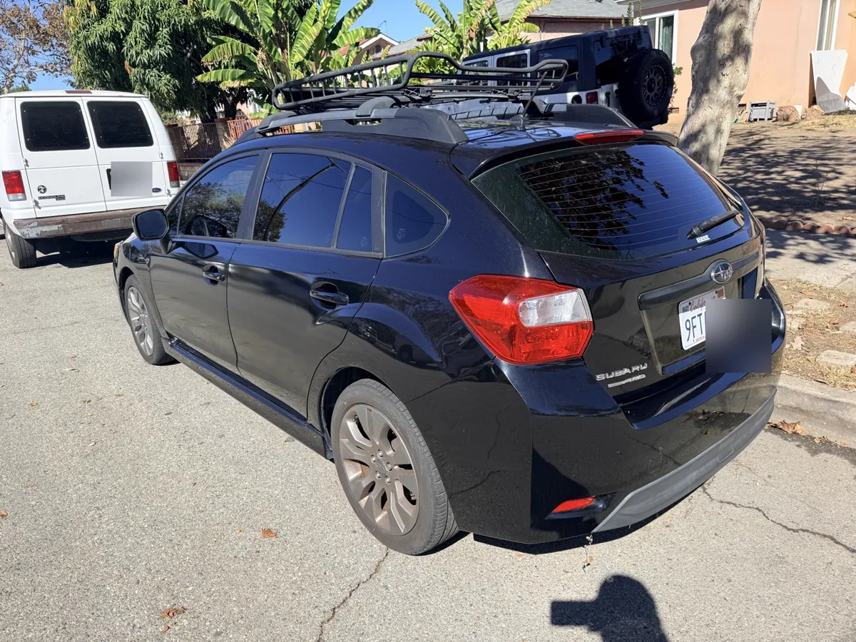 Black Subaru Impreza hatchback, rear three-quarter view