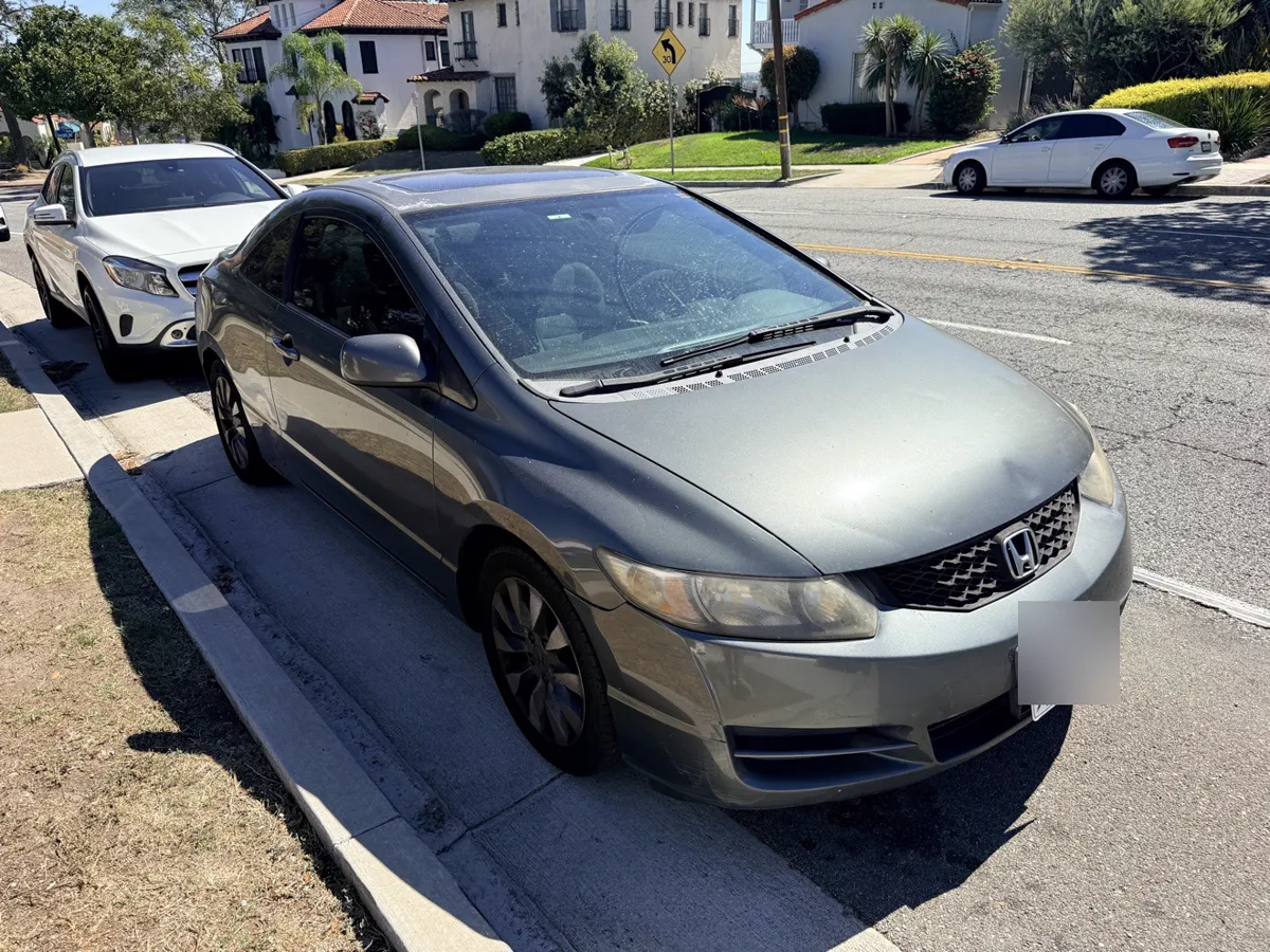 Gray Honda Civic coupe parked at the curb, front three-quarter view